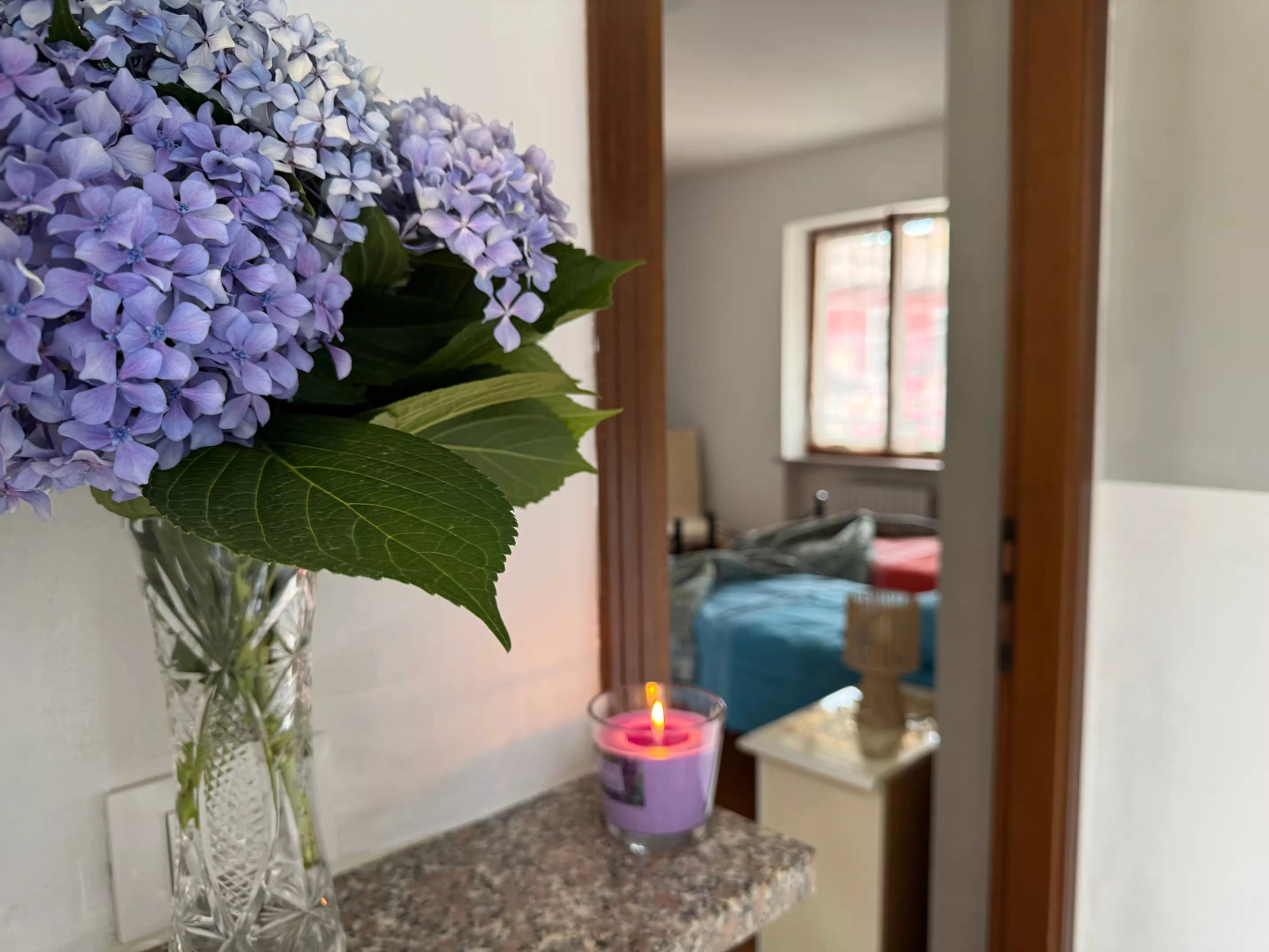 Dettaglio decorativo con ortensie e candela in ambiente accogliente - Villa Sole
